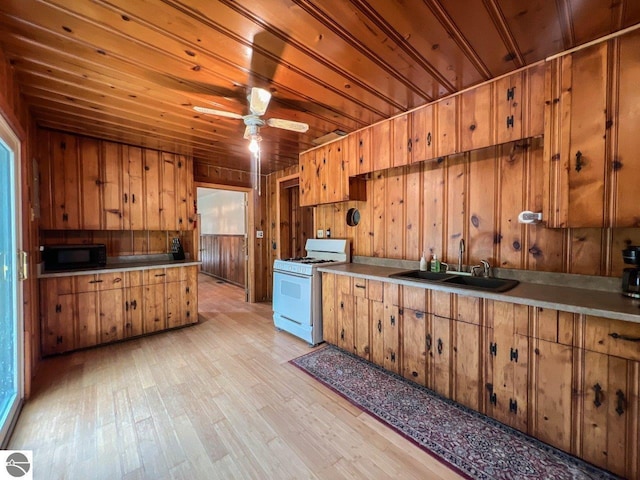 kitchen featuring brown cabinetry, white range with gas stovetop, a sink, and black microwave