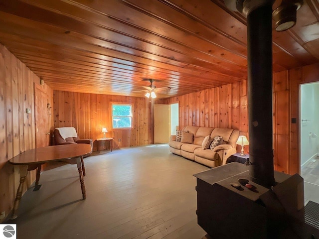 living area featuring wooden ceiling, ceiling fan, wooden walls, and wood finished floors