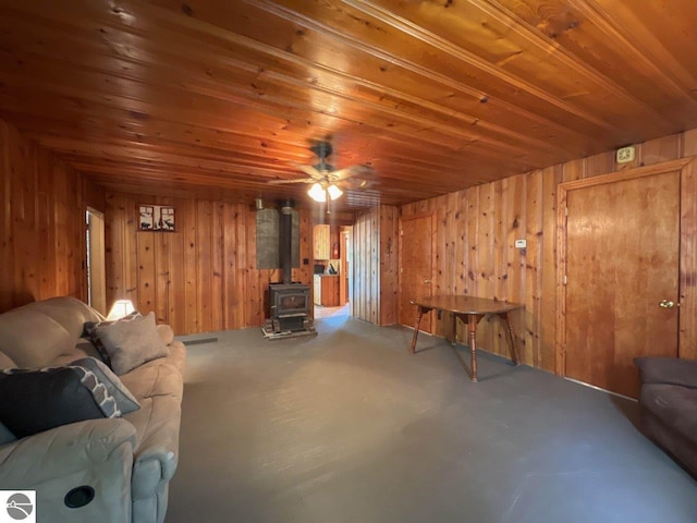 living room with wood ceiling, wooden walls, and a wood stove