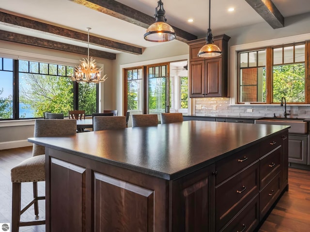 kitchen featuring dark hardwood / wood-style flooring, beamed ceiling, backsplash, and a kitchen island