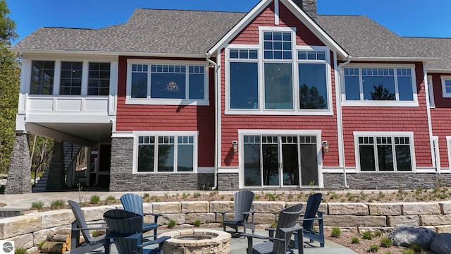 11305 Evergreen, Charlevoix, MI 49720 - back of property with a fire pit, stone siding, a patio, and roof with shingles
