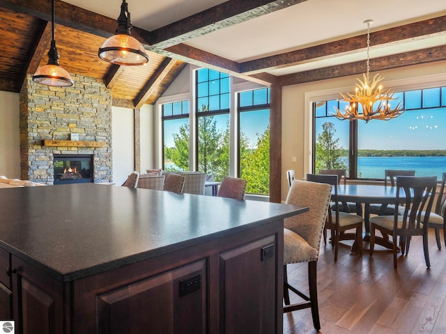 11305 Evergreen, Charlevoix, MI 49720 - dining room with a chandelier, dark wood-style floors, a fireplace, a water view, and wooden ceiling