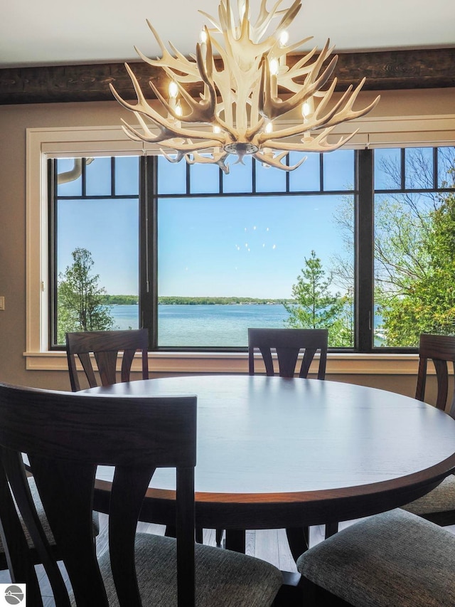 dining room with plenty of natural light, an inviting chandelier, and a water view