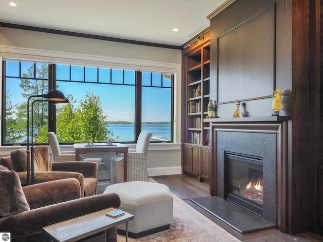 living room with a wealth of natural light, crown molding, a water view, and hardwood / wood-style flooring