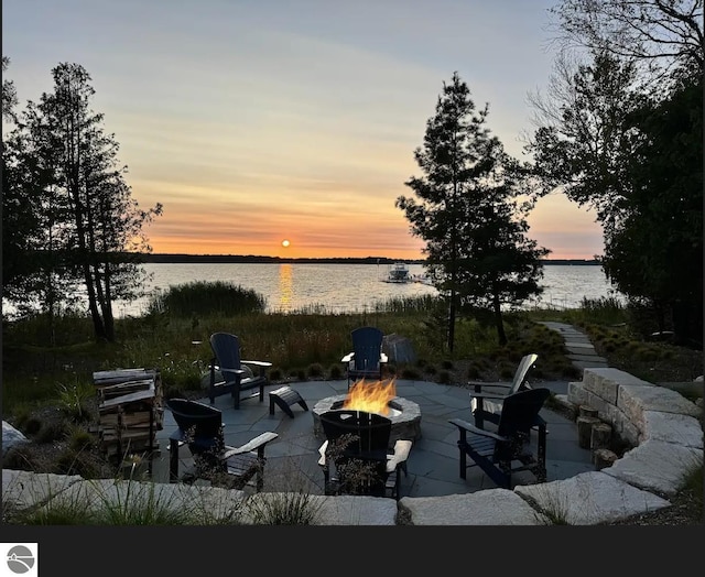 patio terrace at dusk with an outdoor fire pit and a water view