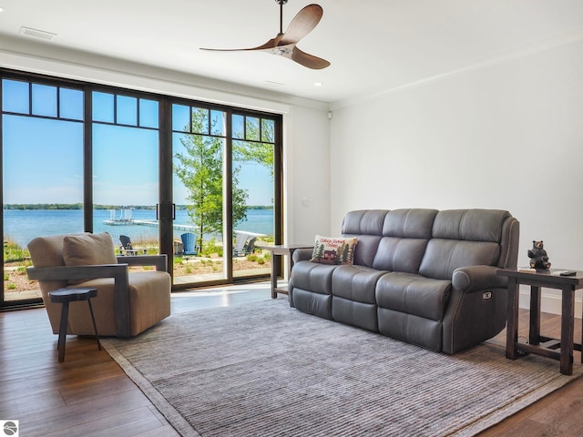 living room featuring a water view, ceiling fan, hardwood / wood-style floors, and ornamental molding