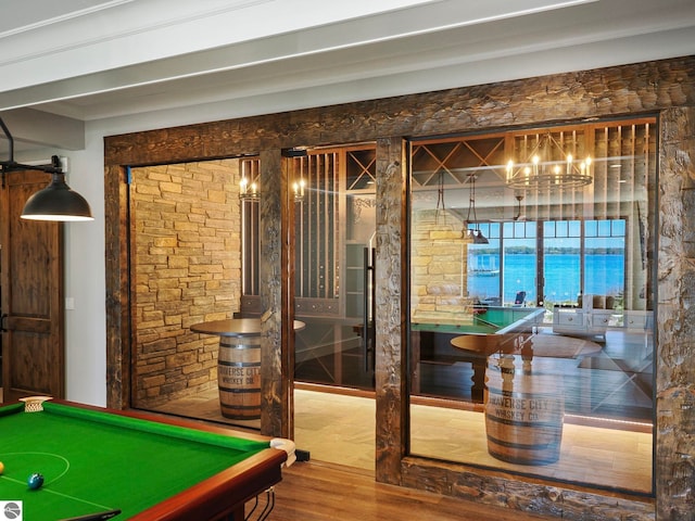 recreation room with hardwood / wood-style flooring, billiards, an inviting chandelier, and a water view