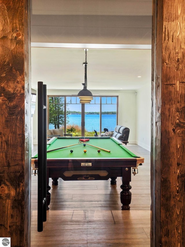 recreation room with a wealth of natural light, light hardwood / wood-style flooring, a water view, and pool table