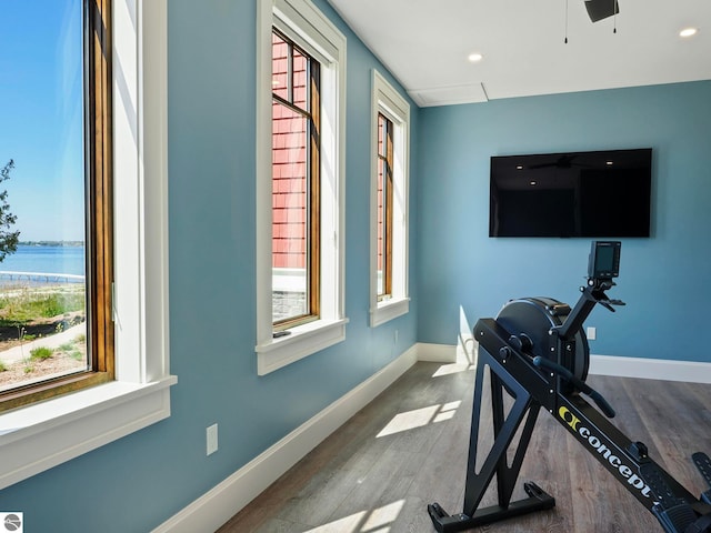 exercise room with hardwood / wood-style flooring, plenty of natural light, and a water view