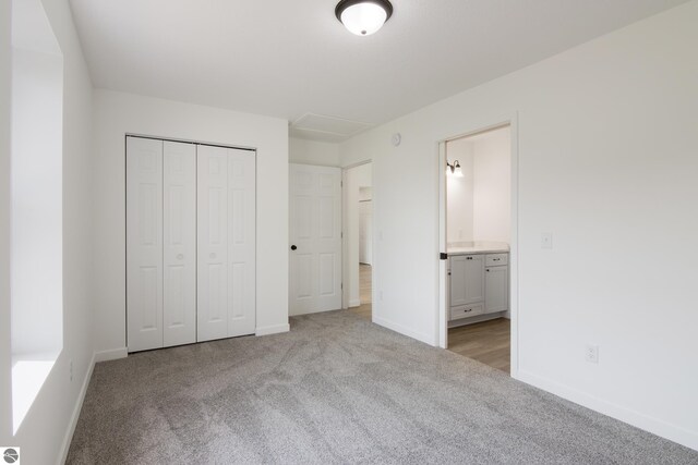 unfurnished bedroom with a closet, connected bathroom, and light colored carpet