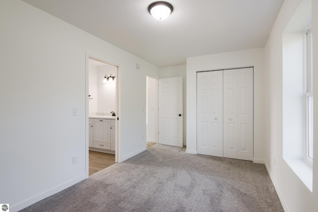 unfurnished bedroom featuring ensuite bath, a closet, and light carpet