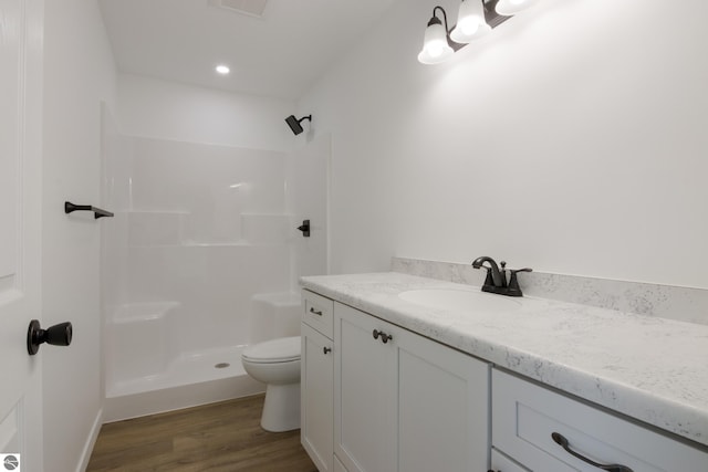 bathroom featuring toilet, hardwood / wood-style floors, vanity, and walk in shower