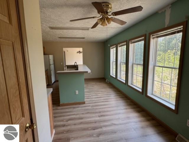 interior space with ceiling fan, a textured ceiling, and light hardwood / wood-style flooring