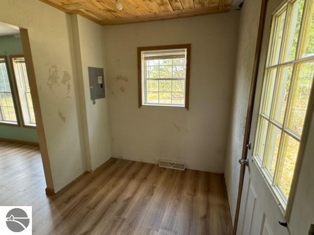 empty room featuring hardwood / wood-style floors, wood ceiling, and electric panel