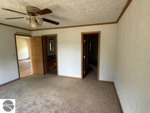 unfurnished bedroom featuring ceiling fan, carpet flooring, a textured ceiling, and ensuite bath