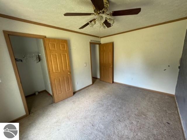 unfurnished bedroom featuring ceiling fan, light colored carpet, a closet, and a textured ceiling