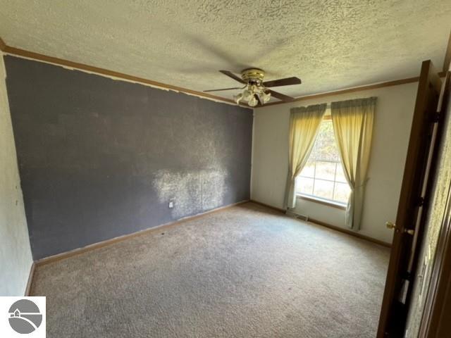 carpeted empty room with ceiling fan and a textured ceiling