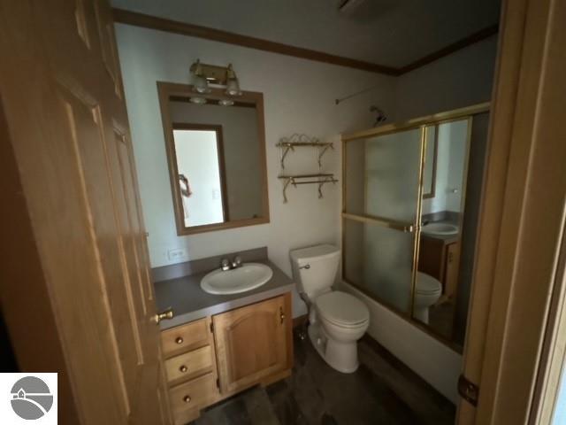 full bathroom featuring toilet, bath / shower combo with glass door, and vanity