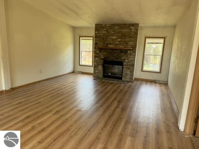 unfurnished living room with a fireplace, hardwood / wood-style flooring, and a wealth of natural light