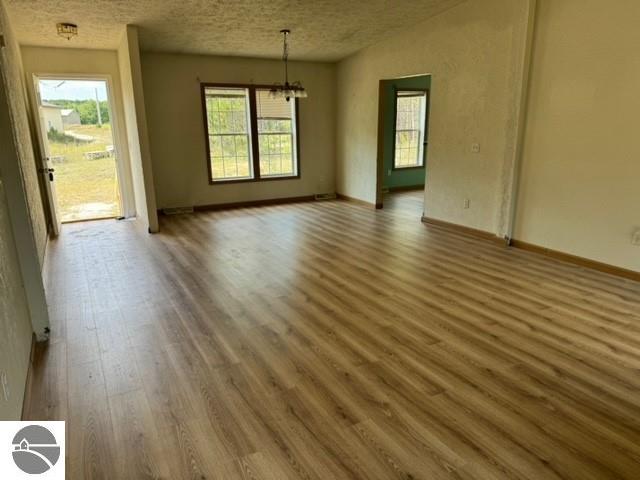 spare room featuring hardwood / wood-style flooring, a textured ceiling, and an inviting chandelier