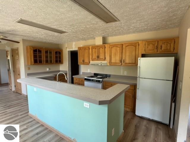 kitchen featuring a center island, hardwood / wood-style floors, sink, a textured ceiling, and white appliances