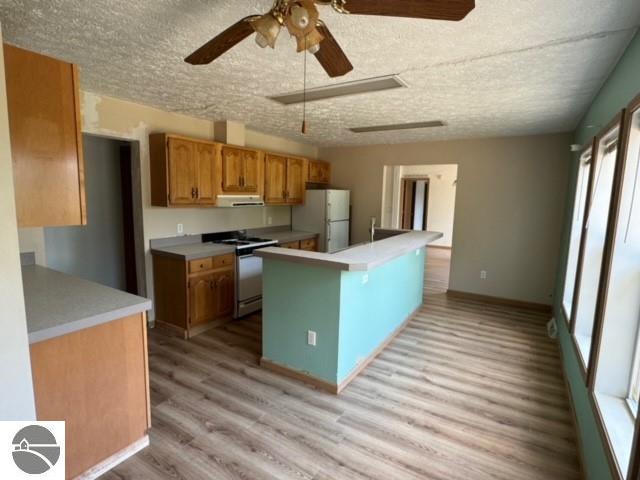 kitchen with ceiling fan, white fridge, light hardwood / wood-style flooring, range, and exhaust hood