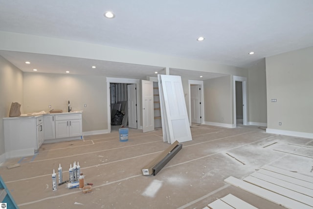 unfurnished living room featuring recessed lighting, a sink, and baseboards