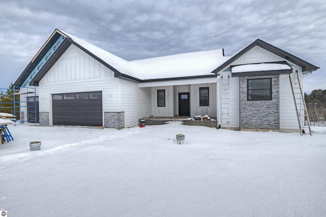 modern inspired farmhouse with a garage, stone siding, and board and batten siding