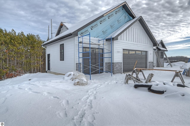 exterior space with board and batten siding, stone siding, and an attached garage