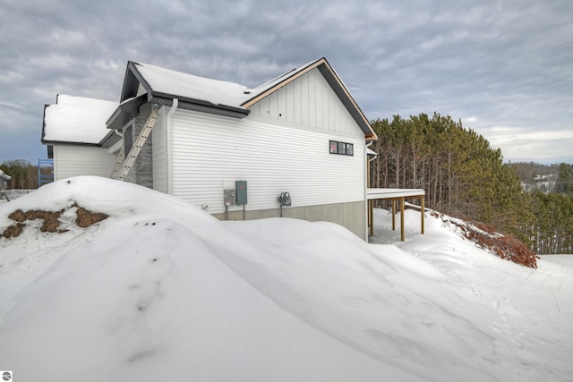 snow covered property with board and batten siding