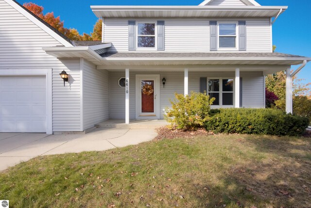 view of property featuring a front lawn, a porch, and a garage