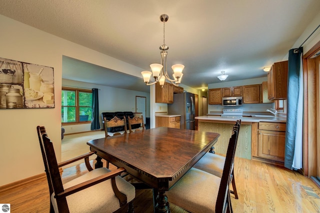 dining space featuring light hardwood / wood-style floors, an inviting chandelier, and sink