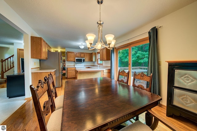 dining space with light wood-type flooring and a notable chandelier