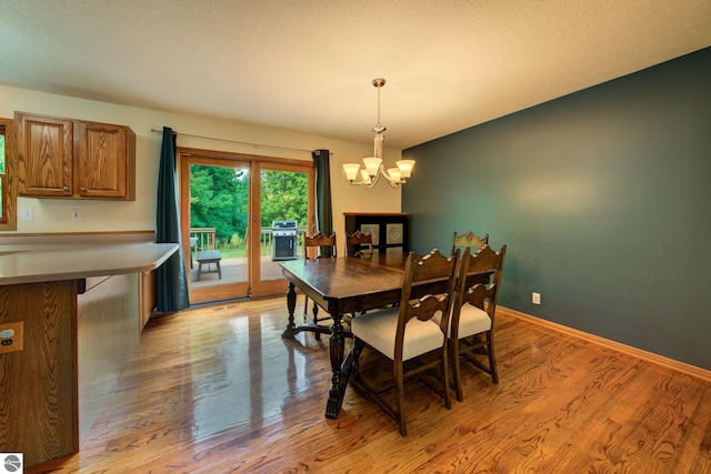 dining area featuring a textured ceiling, light hardwood / wood-style floors, and a notable chandelier