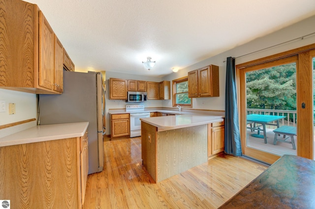 kitchen with sink, light hardwood / wood-style flooring, a textured ceiling, and appliances with stainless steel finishes