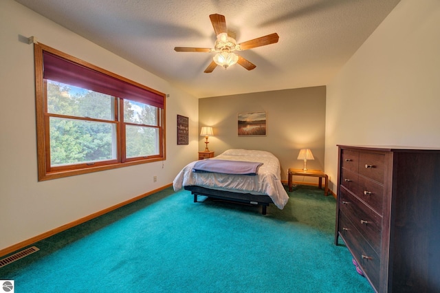 bedroom with ceiling fan, carpet floors, and a textured ceiling