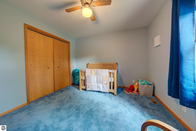 carpeted bedroom featuring ceiling fan, a closet, and a textured ceiling