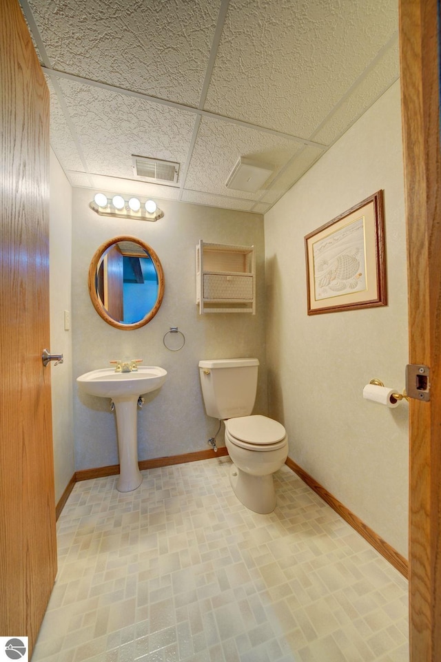 bathroom featuring a drop ceiling and toilet