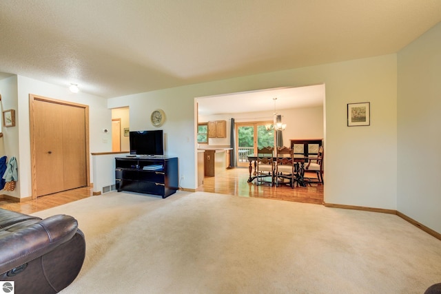 carpeted living room featuring a notable chandelier