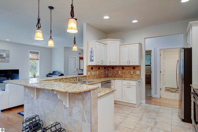 kitchen with light hardwood / wood-style flooring, light stone counters, pendant lighting, and stainless steel appliances