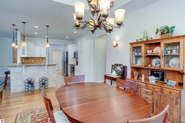 dining area featuring sink, light hardwood / wood-style floors, and a chandelier