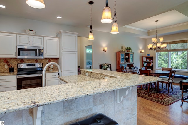 kitchen with light wood-type flooring, a raised ceiling, plenty of natural light, and range with electric cooktop