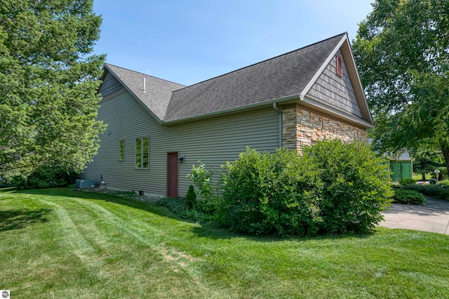 view of side of property featuring central air condition unit and a yard