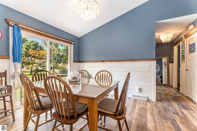 dining room featuring vaulted ceiling, an inviting chandelier, and hardwood / wood-style flooring