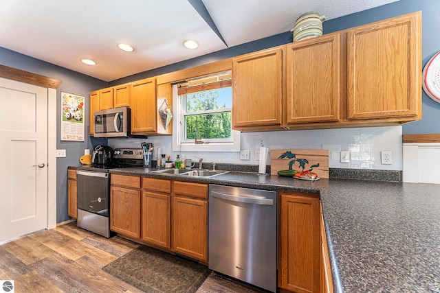 kitchen with light hardwood / wood-style floors, backsplash, sink, and stainless steel appliances