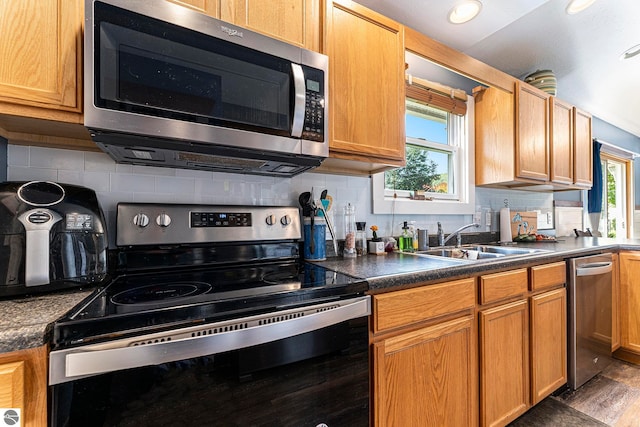 kitchen with appliances with stainless steel finishes, sink, dark wood-type flooring, and decorative backsplash