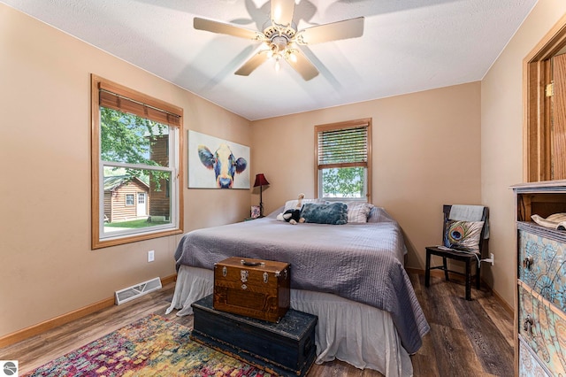 bedroom with ceiling fan, a textured ceiling, and wood-type flooring