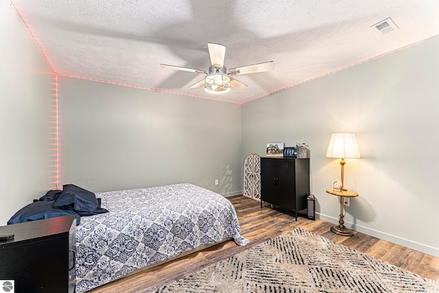 bedroom with ceiling fan, a textured ceiling, and hardwood / wood-style floors