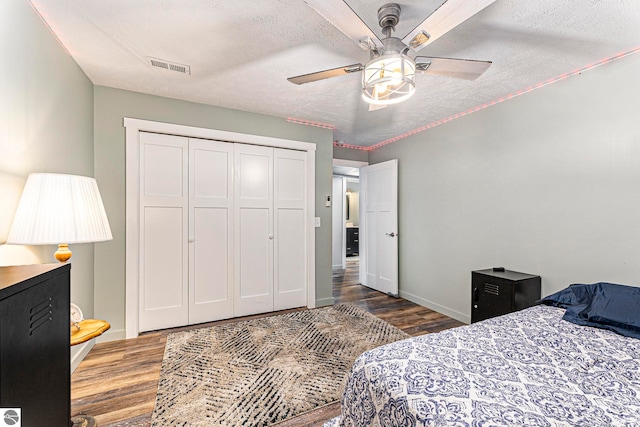 bedroom with a textured ceiling, a closet, ceiling fan, and hardwood / wood-style floors