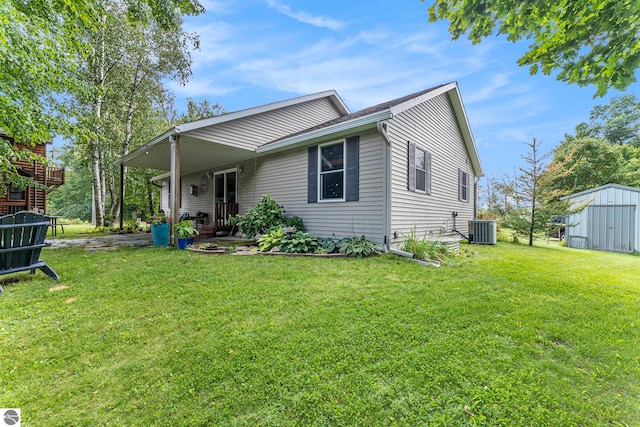 back of house with central AC unit, a shed, and a yard